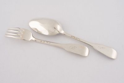 deux cuillères et une fourchette en argent sur une surface blanche