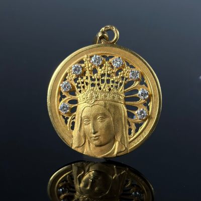 a close up of a gold pendant with a crown on top of it