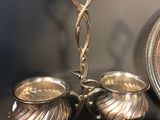 two silver dishes on a table with a mirror in the background