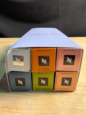 Trois boîtes de café sont posées sur une table en bois, sur fond noir.