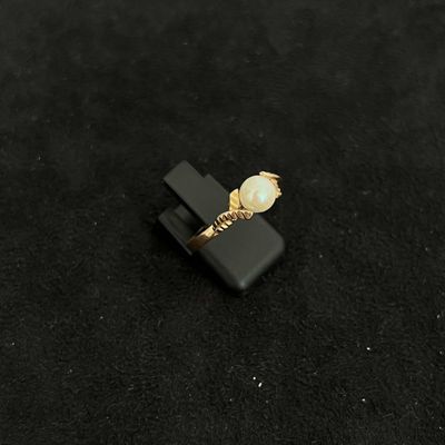 black and gold ring with a pearl on a black surface