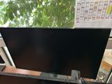 a flat screen tv sitting on a desk in front of a window