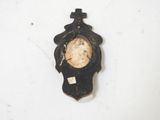 a small clock on the wall with a cross on it