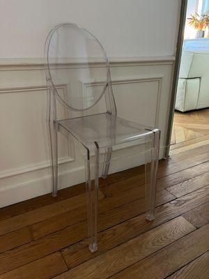 a clear plastic chair sitting in front of a white wall