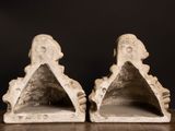 pair of white stone bookends on wooden table against black background