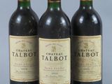 three bottles of red wine are lined up on a gray surface