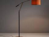 un lampadaire avec un abat-jour orange posé sur une surface blanche