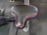 a black seat with red stitching on it in a gym