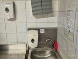 a sink in a public restroom with a paper towel dispenser