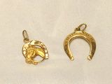a close up of two gold horseshoe charms on a white cloth