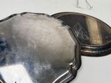 two silver trays sitting on a white table