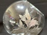 a glass vase with a leaf in it on a black surface