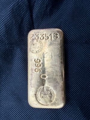 un lingot d'argent portant un poinçon, posé sur un tissu bleu