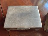 a silver case sitting on a wooden table next to a clock