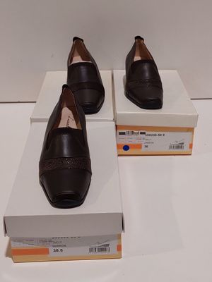 deux paires de chaussures noires posées sur des cartons, sur une surface blanche
