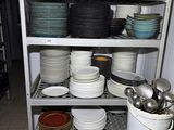 de nombreuses assiettes et casseroles empilées sur une étagère dans une cuisine