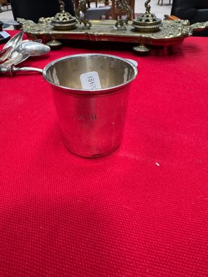 a silver cup sitting on top of a red tablecloth next to a clock