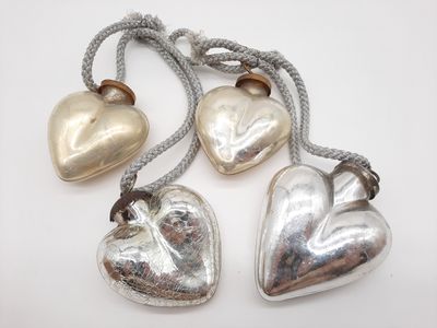 trois clochettes en forme de cœur, en argent et en or, suspendues à un fil