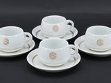quatre tasses à café blanches avec leurs soucoupes, posées sur une table noire