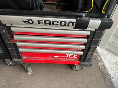 une boîte à outils rouge sur laquelle est apposée une étiquette noire et argentée