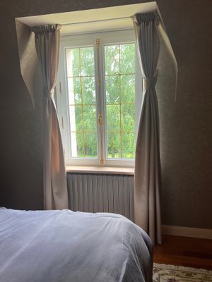 un lit dans une chambre avec une fenêtre et un tapis au sol