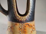 a brown and black vase with a design on it