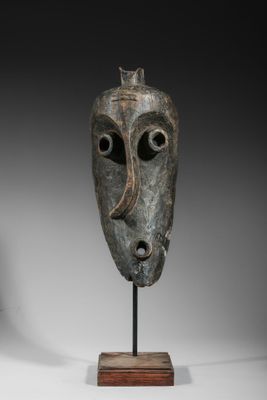 une image représentant un masque en bronze posé sur un socle en bois