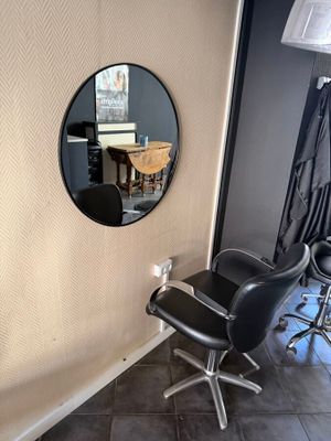 a black chair and a round mirror in a room