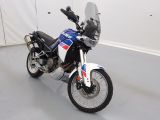 une moto garée dans une pièce aux murs et au sol blancs