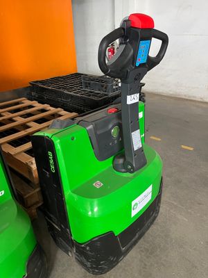 un chariot élévateur vert garé dans un entrepôt