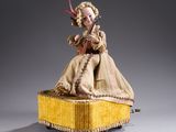an image of a doll sitting on top of a yellow box