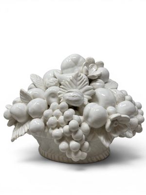 a white vase that has a bunch of fruit in it