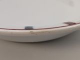a white plate with a red stripe on it on a table