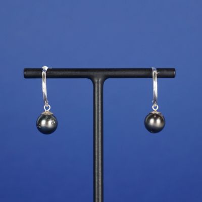 une paire de boucles d'oreilles en forme de boules argentées posées sur un socle noir