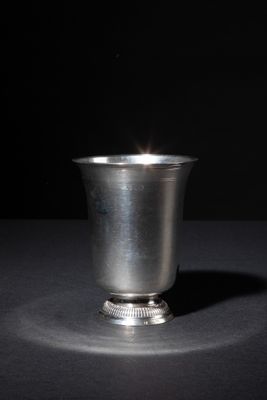 a silver cup sitting on a table with a black background