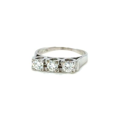 un gros plan d'une bague en diamant à trois pierres sur fond blanc