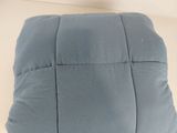 Le coussin est bleu et orné d'un petit motif carré.