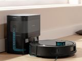 an image of a robotic vacuum cleaner sitting on the floor next to a box