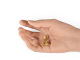 a hand holding a small gold object in it ' s palm