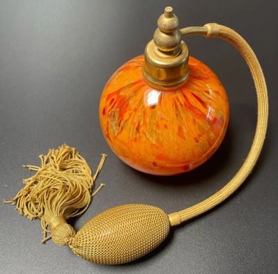 an orange vase with a gold handle and a rope