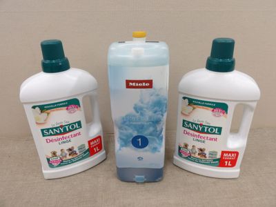 trois bouteilles de Saniti et un flacon de savon posés sur une table