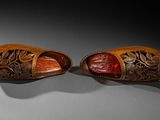 pair of carved wooden shoes on a gray surface