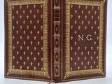 un vieux livre à la couverture dorée et rouge sur un fond blanc