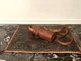 a brown leather bag on a black and white marble floor