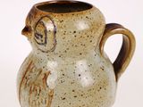 a brown vase with a bird on it on a white surface