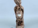 une vieille statue en bois représentant un homme avec une chaîne autour du cou
