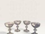 four silver glass goblets and a silver vase on a white surface