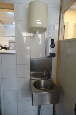 un évier en acier inoxydable dans le coin d'une toilette publique