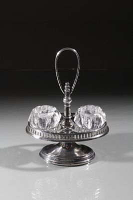 un plat ancien en argent surmonté d'un bol en verre