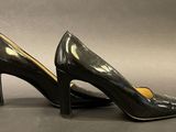 a pair of black high heeled shoes on a gray surface